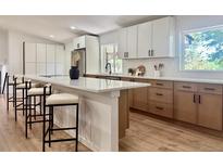 Bright kitchen featuring white cabinetry, an island with seating, modern countertops, and stainless steel appliances at 11351 Quivas Way, Denver, CO 80234