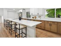 Bright kitchen featuring white cabinets, a spacious quartz island with seating, and modern stainless steel appliances at 11351 Quivas Way, Denver, CO 80234