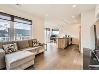 Bright, open living space featuring hardwood floors, a modern kitchen, and comfortable seating next to large windows at 1898 S Bannock St # 307, Denver, CO 80223