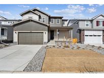 Charming two-story home with a front porch, gray siding, a well-manicured lawn, and an attached two-car garage at 1397 Brookfield Pl, Erie, CO 80026