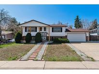 Charming two-story home with landscaped front yard and attached two-car garage on a sunny day at 13472 W Dakota Ave, Lakewood, CO 80228