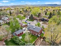 Expansive aerial view of a neighborhood with a brick home, green lawn, mature trees, and mountain views at 2210 Miller St, Lakewood, CO 80215
