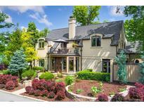 Stunning two-story home with lush landscaping, featuring a charming balcony, elegant architectural details, and mature trees at 6901 E 12Th Ave, Denver, CO 80220