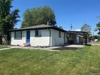 Charming single-story home featuring a well-maintained lawn and a bright blue front door at 6193 Holland St, Arvada, CO 80004