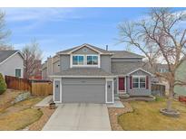 Charming two-story home with a well-manicured lawn, attached two-car garage and a red front door at 13472 Monroe St, Thornton, CO 80241
