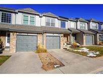 Three-unit townhouse complex with grey doors and stone accents at 2245 E 103Rd Pl, Thornton, CO 80229