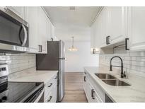 Modern kitchen features white cabinets, stainless steel appliances, and quartz countertops at 7755 E Quincy Ave # 301A2, Denver, CO 80237