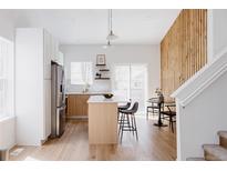 Bright modern kitchen featuring an island with seating, stainless steel appliances, and light wood floors at 4264 Thorndyke Pl, Broomfield, CO 80020