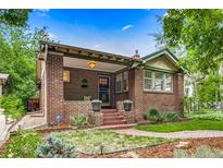 Charming brick home featuring a covered porch, red brick stairs, and lovely landscaped front yard at 840 S Corona St, Denver, CO 80209