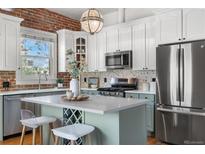Modern kitchen features stainless appliances, white cabinets, a central island with a wine rack and quartz countertops at 624 E 18Th Ave # 3, Denver, CO 80203