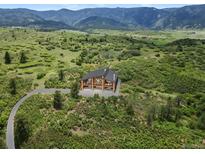 Stunning modern home with wood and glass design, set amongst lush greenery, offering panoramic mountain views at 8821 S Perry Park Rd, Larkspur, CO 80118