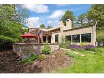 Charming home exterior featuring a stone retaining wall, pergola, and lush landscaping at 2107 Ridge Plaza Dr, Castle Rock, CO 80108
