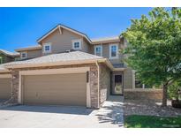Inviting two-story home with a two car garage, stone accents, manicured lawn, and mature shade tree at 22002 E Irish Dr, Aurora, CO 80016