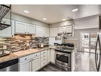 Bright kitchen features granite counters, mosaic backsplash, and stainless-steel appliances at 2974 S Parker Ct, Aurora, CO 80014