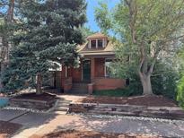 Charming brick home with mature trees, a landscaped front yard, and inviting curb appeal at 588 S Grant St, Denver, CO 80209