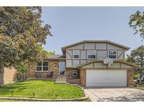 Charming two-story home with a brick and gray exterior, lush green lawn, and a basketball hoop above the garage at 16602 E Gunnison Pl, Aurora, CO 80017