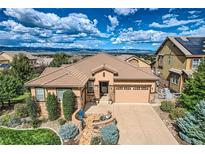 An aerial view of a house with a large yard, two-car garage, and mountain views at 10443 Skyreach Way, Highlands Ranch, CO 80126