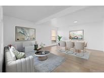 Bright living room with modern decor, light wood floors, and an adjacent dining area perfect for entertaining guests at 3663 S Sheridan Blvd # I8, Denver, CO 80235