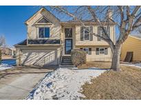 Tan two-story house with a double car garage and snow covered front yard at 2808 S Fundy St, Aurora, CO 80013