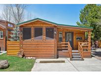 Charming log cabin with covered porch, stone accents, and a well-maintained lawn at 85 Revett Dr # 40, Breckenridge, CO 80424