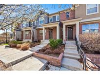 Charming brick townhomes featuring covered front porches, landscaping, and inviting entryways with steps leading to the front doors at 7422 E 7Th Ave # 14, Denver, CO 80230