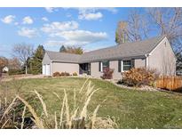 Charming single-story home featuring a well-manicured lawn, gray siding, and a gray tile roof under a blue sky at 7107 E Costilla Dr, Centennial, CO 80112