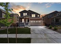 Inviting two-story home featuring a well-manicured lawn and a spacious two-car garage at sunset at 13221 E 110Th Pl, Commerce City, CO 80022
