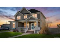 Charming two-story home featuring a welcoming front porch, manicured lawn, and traditional design elements at 9515 E 109Th Cir, Commerce City, CO 80640