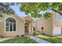 Inviting two-story home with a well-manicured lawn, arched window, and brick pathway at 7452 S Utica St, Littleton, CO 80128