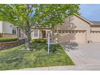 Charming brick home with manicured lawn, mature tree, and a three-car garage at 29 Woodland Cir, Highlands Ranch, CO 80126