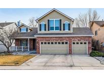 Charming two-story home featuring a brick facade, large windows, and a two-car garage at 12690 W 84Th Cir, Arvada, CO 80005