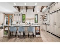Bright kitchen boasts a large island, pendant lights and beams above an elegant range hood at 2891 E Alameda Ave, Denver, CO 80209