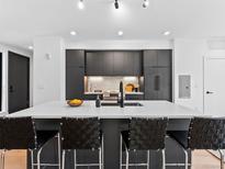 Modern kitchen features a spacious island with seating, sleek black cabinetry, and stainless steel appliances at 1601 Park Ave # 212, Denver, CO 80218