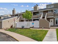 Inviting townhome featuring a well-maintained front yard with a white picket fence and exterior stairs at 8095 E Colorado Ave # 5, Denver, CO 80231