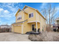 Inviting two-story yellow home featuring a covered front porch and attached garage at 740 Boxwood Ln, Longmont, CO 80503