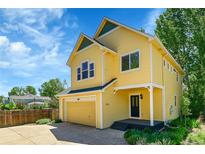 Charming yellow two-story home featuring a well-manicured lawn and attached garage at 740 Boxwood Ln, Longmont, CO 80503