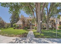 Inviting multi-level condo with landscaped grounds, mature trees, and a sidewalk leading to the entrance at 13704 E Lehigh Ave # D, Aurora, CO 80014