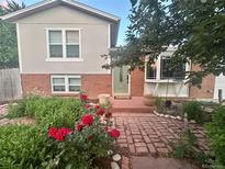 Charming home with a beautiful brick facade, lovely front garden, and a welcoming green front door at 6248 W 75Th, Arvada, CO 80003
