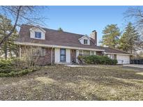 Charming brick home featuring dormer windows, mature trees, and an attached two car garage at 10040 W 78Th Ave, Arvada, CO 80005