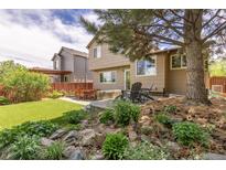 Landscaped backyard featuring a patio with outdoor seating and artificial turf at 2587 Foothills Canyon Ct, Highlands Ranch, CO 80129