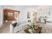 Bright living room with exposed brick wall, white sofa, and open floor plan to the dining area at 2767 W 38Th Ave, Denver, CO 80211