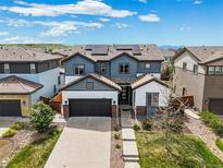 Inviting two-story home with a gray garage door, gray and white siding, professional landscaping, and mountain views at 10934 Touchstone Loop, Parker, CO 80134