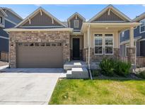 Charming single Gathering home featuring stone accents, a two-car garage, and a well-maintained lawn at 16448 E 111Th Pl, Commerce City, CO 80022