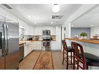 Updated kitchen with white cabinets, stainless appliances, breakfast bar, and tile floor at 4315 S Elati St, Englewood, CO 80110