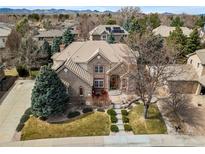 Beautiful brick home featuring professional landscaping and a large front yard, with scenic mountain views in the background at 7425 S Utica St, Littleton, CO 80128