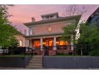 Stately two-story home with a brick facade, covered porch with columns, and well-maintained front yard at dusk at 747 N Downing St, Denver, CO 80218