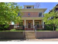 Charming two-story brick home featuring a covered porch, iron fence, and manicured landscaping at 747 N Downing St, Denver, CO 80218