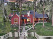 Charming red two-story home with a white picket fence and a landscaped front yard at 102 S High St, Breckenridge, CO 80424