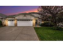 Charming home featuring a three car garage, brick accents, well-maintained landscaping, and a beautiful sky at dusk at 22778 E Alamo Ln, Aurora, CO 80015