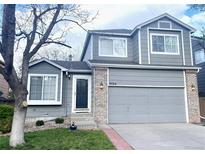 Charming two-story home featuring a gray exterior with brick accents and an attached two-car garage at 9724 Cove Creek Dr, Highlands Ranch, CO 80129